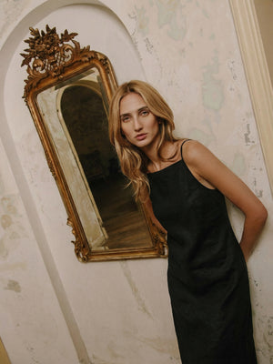 A simple black linen slip dress with thin straps and a midi length.