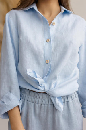 Close-up of breathable linen fabric and collared neckline, ice blue button-down shirt, wooden buttons.