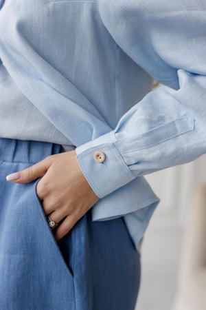 Close-up of light blue buttoned sleeve detail paired with denim blue linen shorts, emphasizing the natural linen texture and craftsmanship.