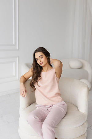 Model in ash pink linen tank top, sitting, comfortable summer wear.
