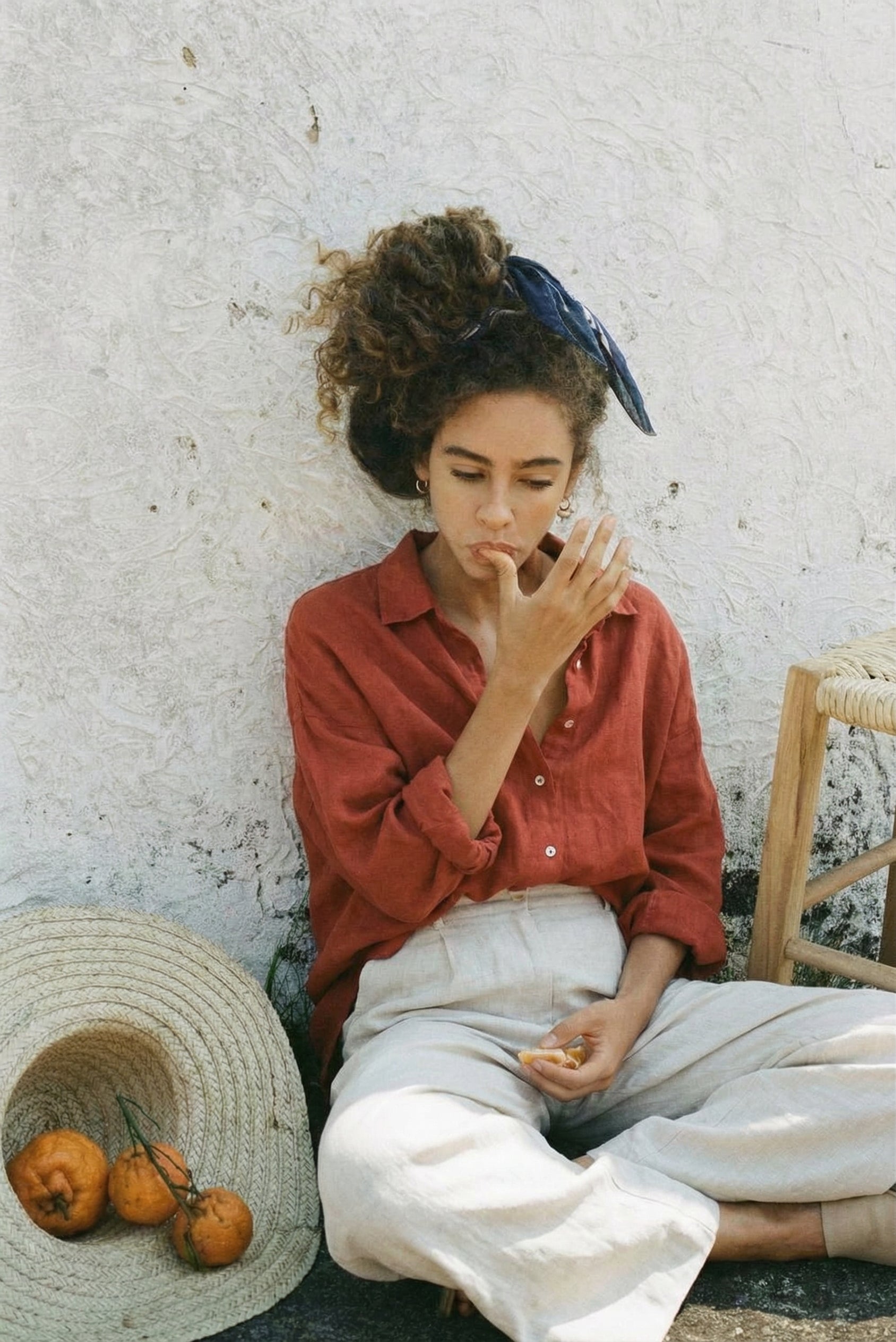 Relaxed lifestyle shot of the SOFIJA oversized linen shirt in Clay, styled with white linen trousers for a boho summer aesthetic.