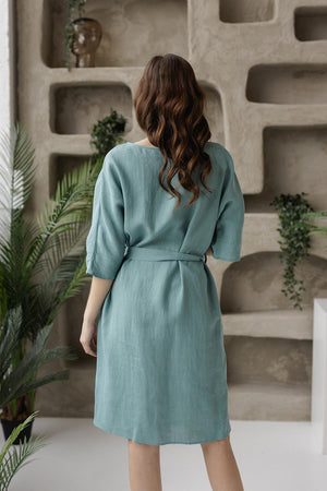 Back view of knee-length linen tunic dress, adjustable belted waist, breathable fabric, three-quarter sleeves.