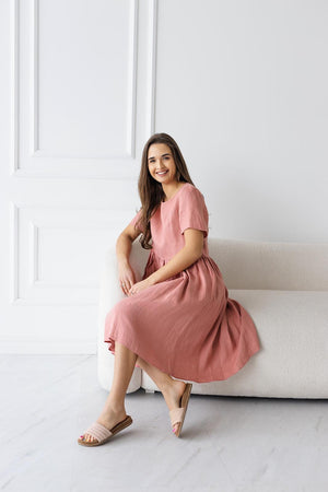 Full view of blush salmon linen midi dress; round neckline, short sleeves, gathered waist, casual elegance.