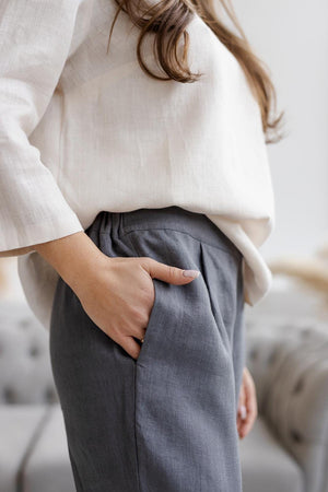 Close-up of dark gray linen pants showing a deep side pocket and soft, breathable fabric with a relaxed fit.