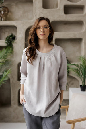 Closer front shot of the Calyra gray linen tunic, highlighting the round neckline with delicate pleats.