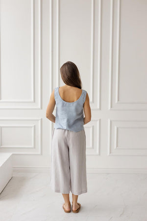 Light gray linen wide-leg culottes, back view. Flowing cut, elastic waistband. Woman standing.