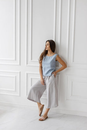 Light gray linen culottes, full outfit. Wide-leg, relaxed style. Woman standing, neutral sandals.
