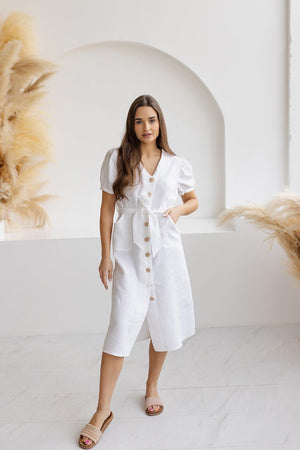 Model wearing a white puff sleeve linen midi dress with a button-down front and tie waist, showcasing a casual summer look.