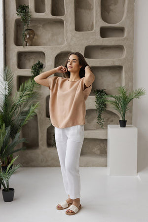 Woman wearing a taupe linen blouse in a relaxed, boxy fit, moving naturally for a fluid and comfortable look. Made from 100% natural linen for breathable, all-day wear.