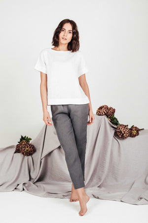 Front view of woman wearing white boxy linen top paired with grey linen pants