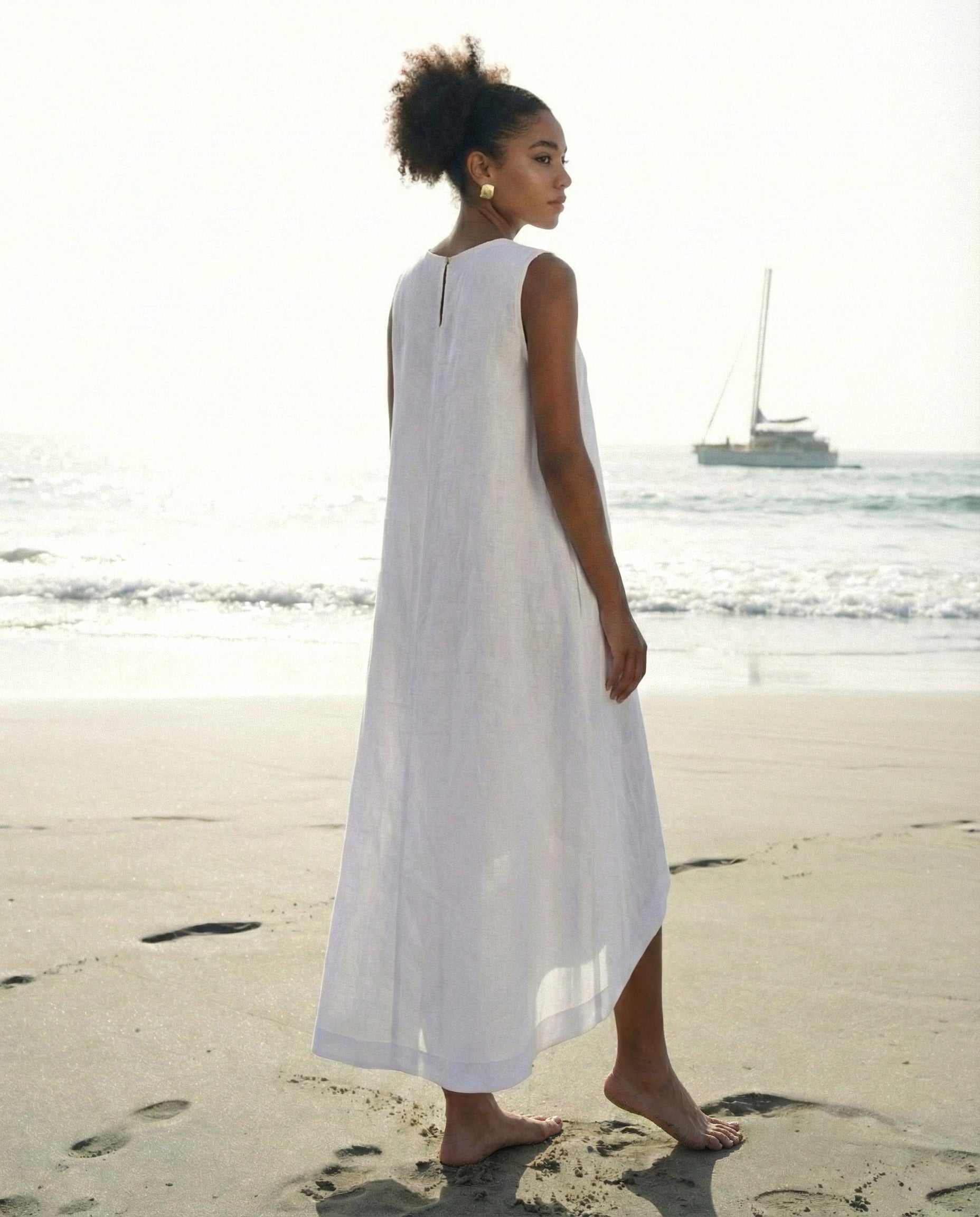 Back view of a sleeveless white linen dress showing the asymmetrical high-low hemline and keyhole detail.