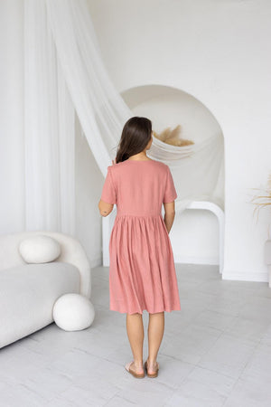 Back view of blush salmon linen midi dress; short sleeves, relaxed fit, flowing midi hem.