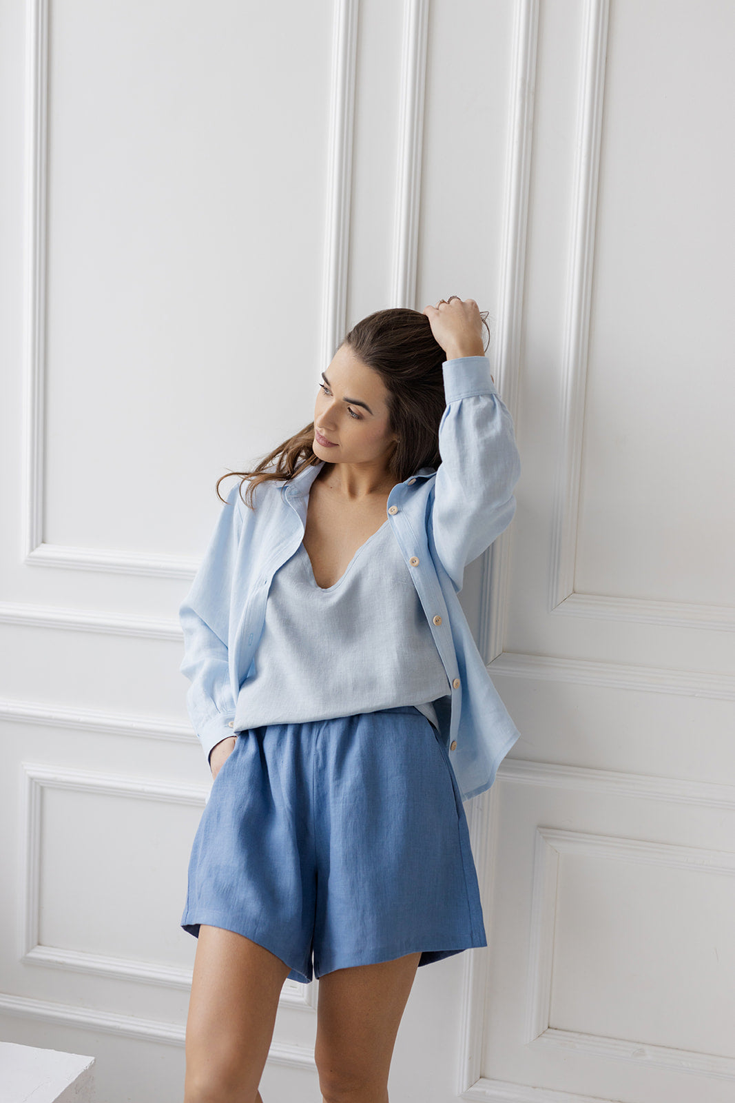 Model wearing denim blue linen shorts with an elastic waistband and relaxed fit, styled with a light blue top.