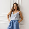 Front view of a woman wearing a dusty blue sleeveless linen cami top with a V-neck, paired with comfortable blue linen shorts, presenting a casual and airy summer outfit.