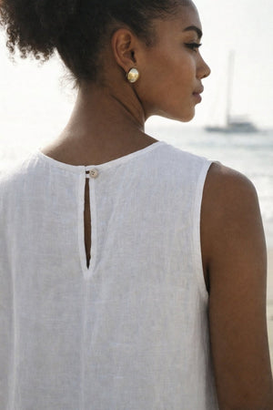 Woman wearing asymmetrical white linen summer dress with pockets.