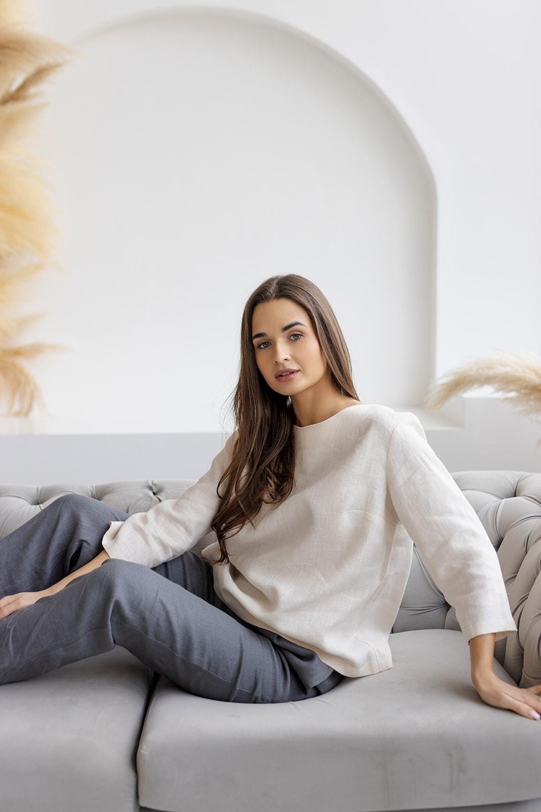 Off-white breathable linen blouse, relaxed fit, shown on model sitting.