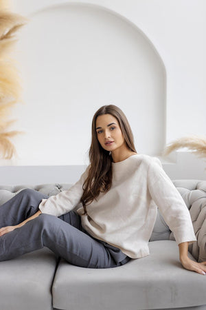 Off-white breathable linen blouse, relaxed fit, shown on model sitting.