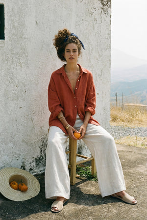 Front view of the SOFIJA oversized linen shirt in Clay, styled with white wide-leg trousers and summer sandals.