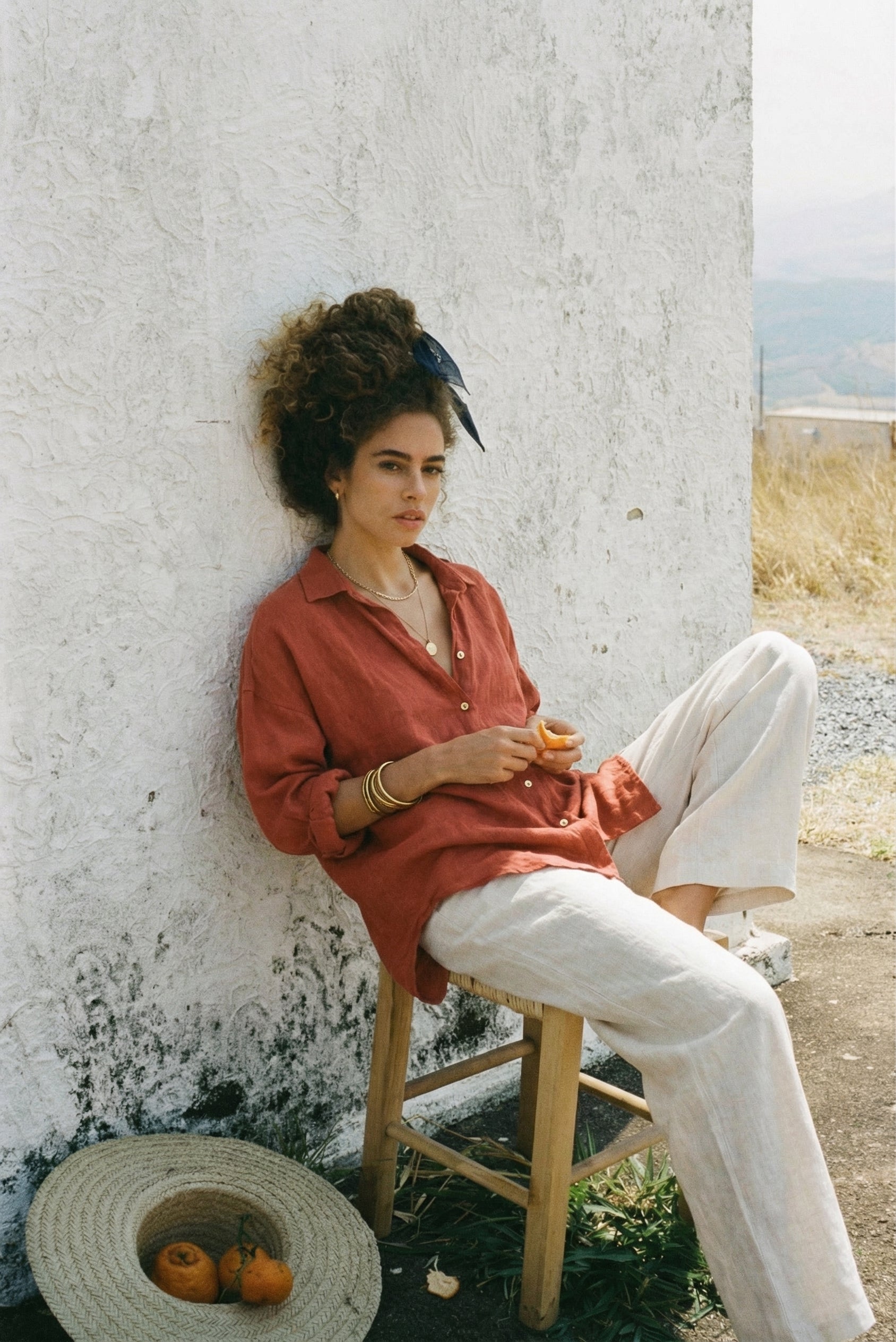 Model wearing the SOFIJA oversized long sleeve linen shirt in Clay, paired with white linen trousers.