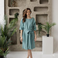Model in belted linen tunic dress with pockets, relaxed fit, three-quarter sleeves.