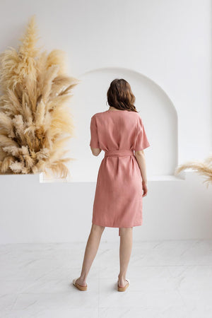 Back view of a blush salmon linen wrap dress, featuring a knee-length design, a fabric tie belt, and a relaxed fit. Crafted from high-quality, breathable linen for everyday elegance.