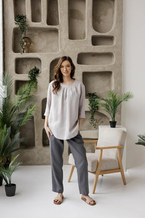 Full-length front view of a model wearing the Calyra light gray linen tunic, showing its relaxed fit and 3/4 sleeves.