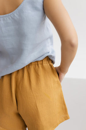 Close-up of mustard linen shorts, showing elastic waistband and soft linen texture.