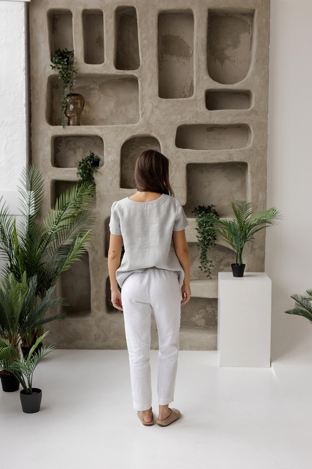 Rear view of a woman in a dusty gray linen blouse, showcasing its minimalist design, breathable fabric, and relaxed drape.