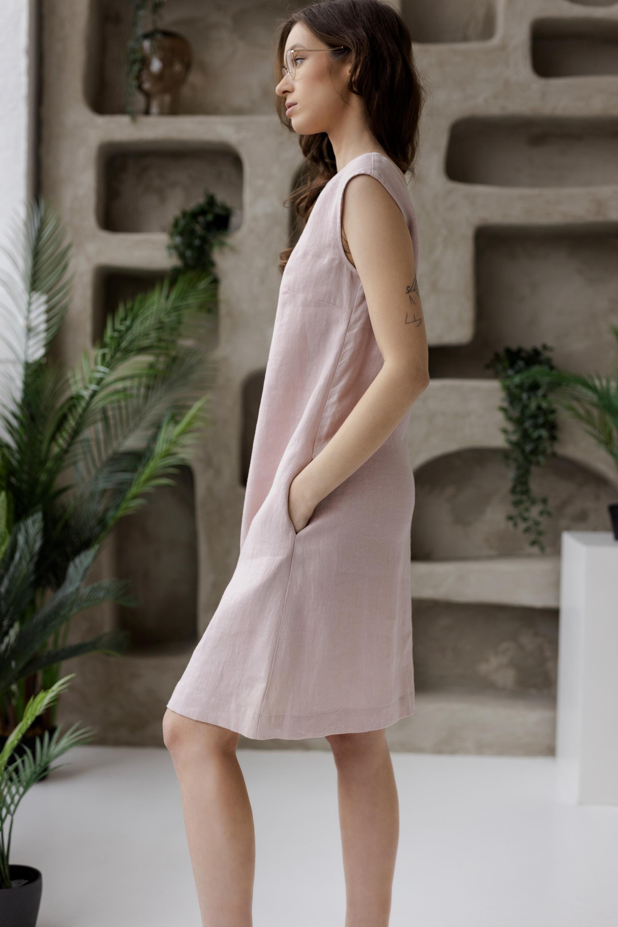 Sleeveless linen shift dress with pockets, dusty rose, minimalist background.