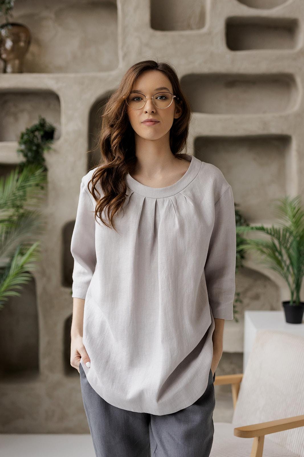 Closer front shot of the Calyra gray linen tunic, highlighting the round neckline with delicate pleats.