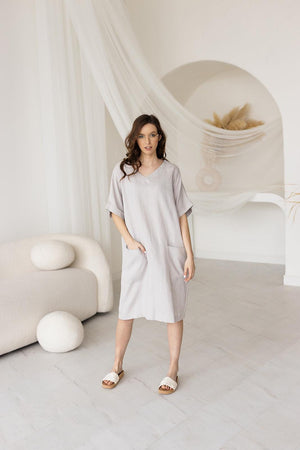 Light gray linen shift dress with a V-neckline, loose fit, and rolled-up sleeves. Mid-length casual dress with deep front pockets, ideal for summer, loungewear, or everyday wear