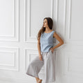 Light gray linen culottes, full outfit. Wide-leg, relaxed style. Woman standing, neutral sandals.