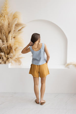 Mustard linen shorts, back view, styled in a minimalist setting with natural pampas grass decor.