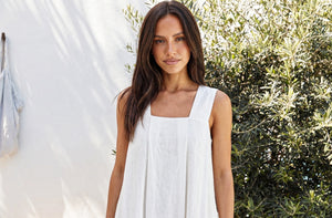 Close-up portrait of the SonFre ONA white linen dress highlighting the structured square neckline, wide shoulder straps, and soft woven texture.