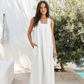 Model wearing the SonFre ONA sleeveless white linen trapeze maxi dress with a square neck and side pockets, standing outdoors.