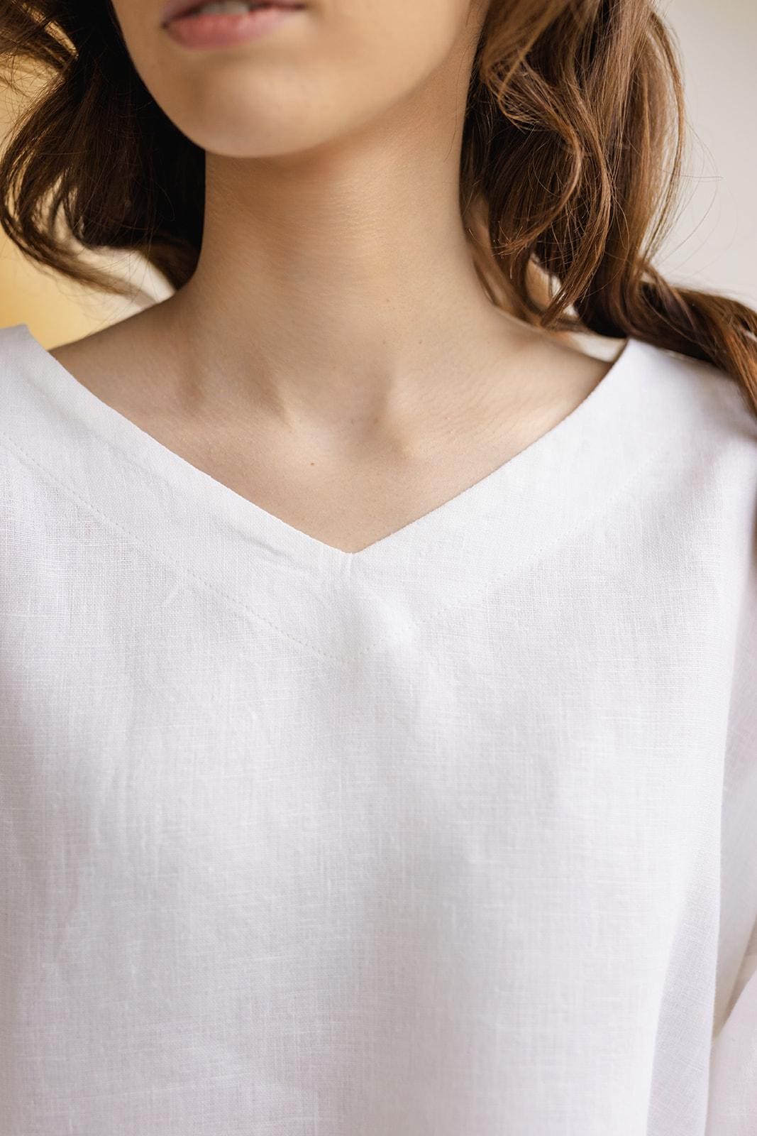 Close-up of Solvia white linen blouse V-neck, fine medium weight linen weave, minimalist stitching.