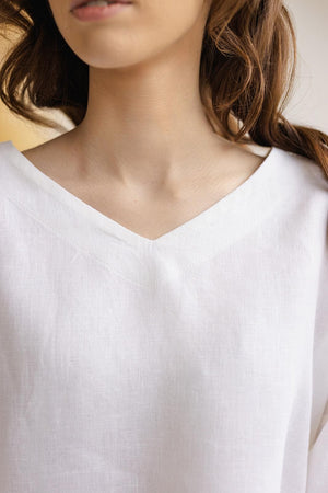 Close-up of Solvia white linen blouse V-neck, fine medium weight linen weave, minimalist stitching.