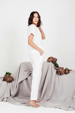 Woman modeling matching set of white linen boxy blouse and relaxed-fit white linen pants