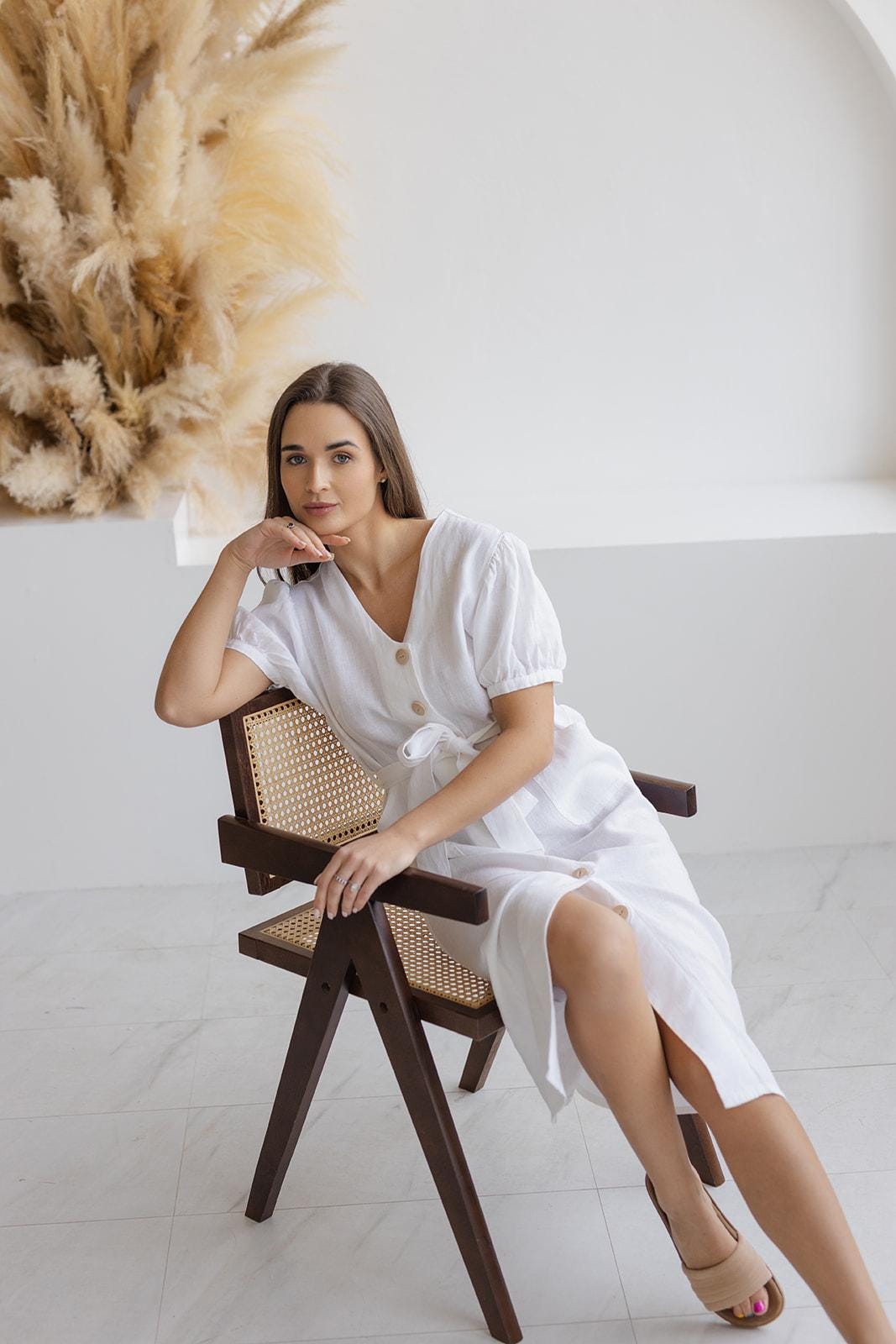 A-line white linen midi dress with a button-down front, puff sleeves, and a tie waist, offering a timeless and versatile summer style.