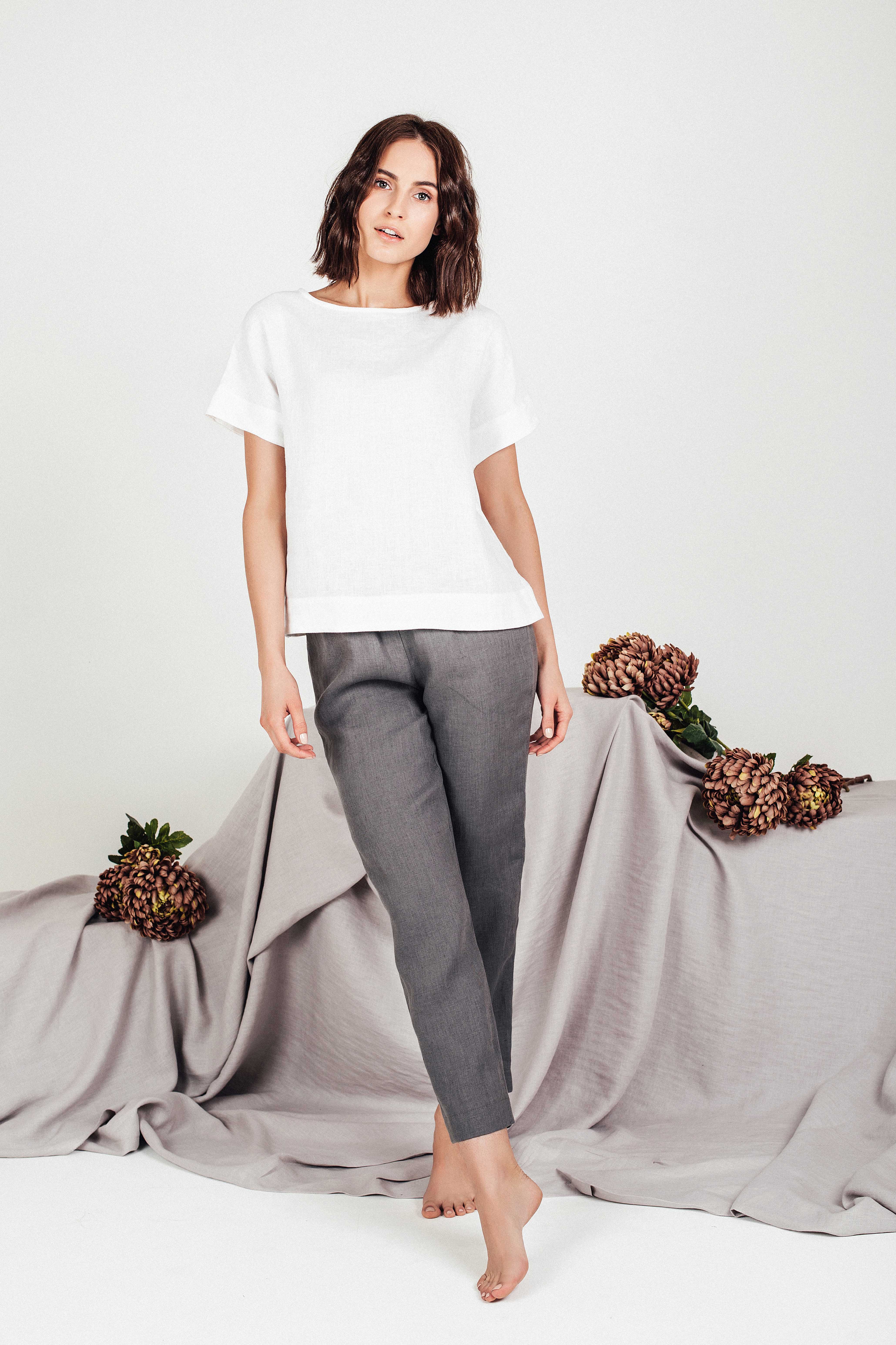 Front view of woman wearing white boxy linen top paired with grey linen pants