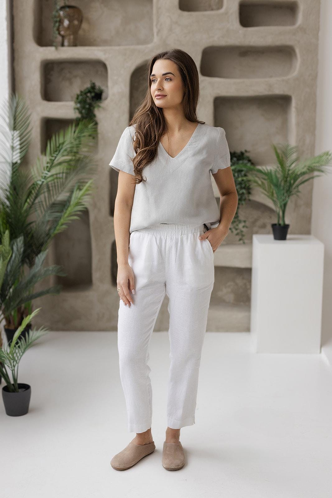 White linen pants styled with a gray linen blouse in a modern, minimalist room, perfect for summer, vacation, or casual everyday wear